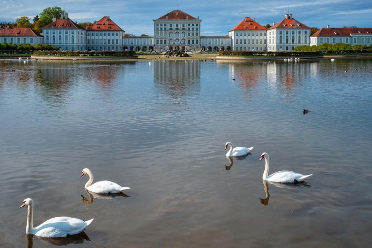 Sehenswürdigkeiten in München: Blick auf das Schloss Nymphenburg mit See und Schwänen im Vordergrund