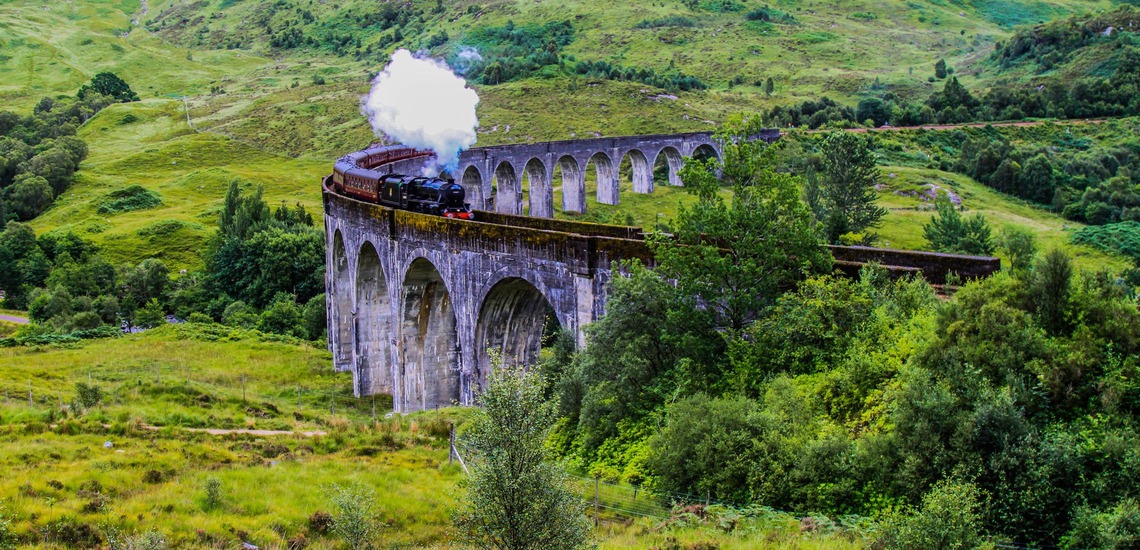 Nachhaltig reisen: Slow Travelling mit der West Highland Line in Schottland. Blick auf den Zug auf dem Glenfinnan Viadukt. 