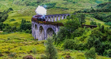 Nachhaltig reisen: Slow Travelling mit der West Highland Line in Schottland. Blick auf den Zug auf dem Glenfinnan Viadukt. 