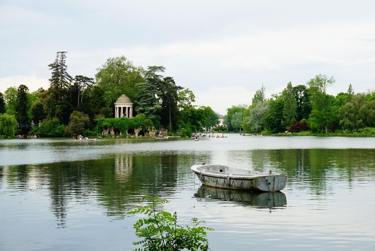 Zu den Sehenswürdigkeiten von Paris gehört der Bois de Vincennes. Im Bild sieht man einen See samt Ruderboot, im Hintergrund das Grün des Parks. 