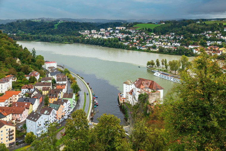 Zu den Passau Sehenswürdigkeiten gehört der Dreiflüsseeck. Auf dem Bild sieht man die Stelle, wo Donau, Inn und Ilz zusammenfließen und sich das unterschiedlich gefärbte Wasser der Flüsse vermischt. 