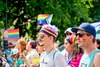 Top Queer Events Europa: Beim Christopher Street Day in Budapest sieht man mehrere Männer in der Parade, die sich mit Regenbögen im Gesicht geschminkt haben. Im Hintergrund werden Regebogen-Flaggen geschwenkt.  