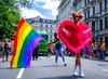 Top Queer-Events Europa: Beim Christopher Street Day in München wird bei der Parade eine Regenbogenfahne geschwenkt. Im Vordergrund geht ein als Herz verkleidete Person. 