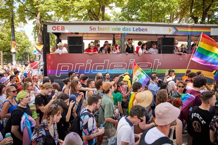 Top Queer-Events Europa: Bei der Vienna Pride und dem Christopher Street Day tanzen Menschen auf der Straße. Im Hintergrund sieht man den ÖBB pridejet, ein Fahrzeug der Parade. 