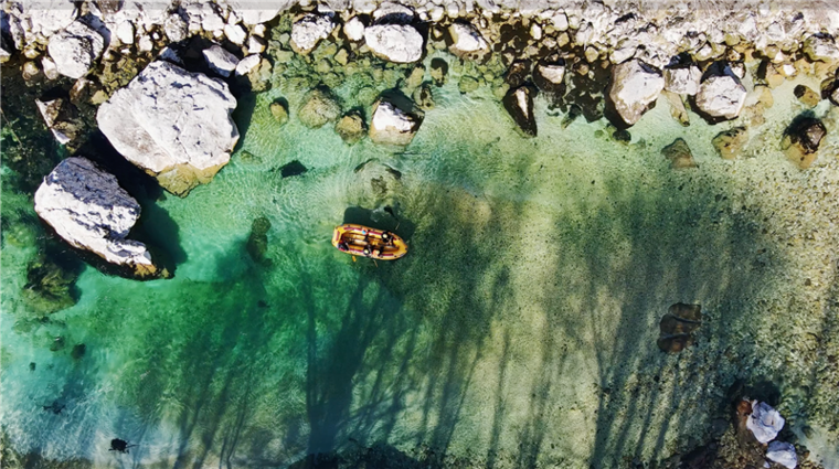 Reise planen: Im Bild das Soča Tal in Slowenien, dass am besten außerhalb der Saison zu bereisen ist! Ein Boot treibt im türkisen Wasser des Flusses. 
