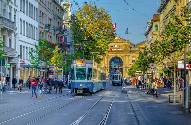 Zu den Sehenswürdigkeiten in Zürich gehört die Bahnhofstraße. Am Bild zu sehen die Straße an einem herbstlichen Tag mit flanierenden Menschen. 