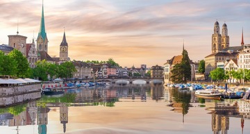 Sehenswürdigkeiten in Zürich: Abendlicher Blick auf die Innenstadt von Zürich vom Wasser aus. 