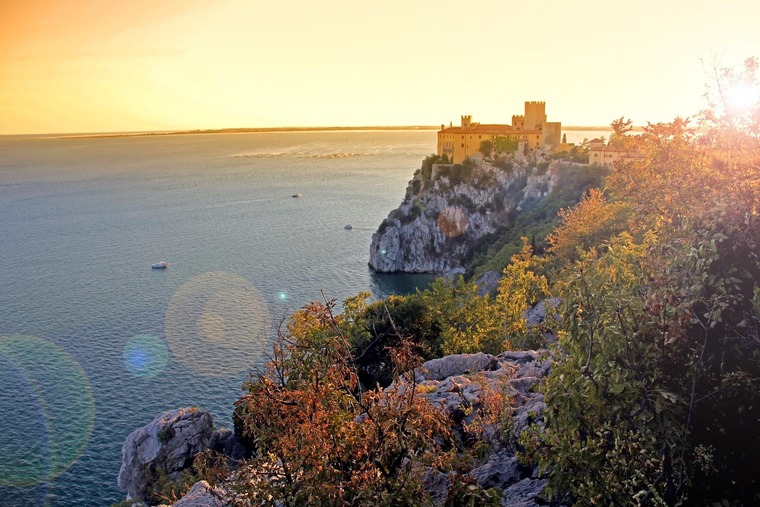 Triest Sehenswürdigkeiten: Der Rilkeweg in Duino führt zum Schloss Duino, hier im Abendlicht zu sehen. 