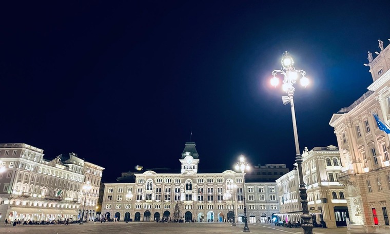 Triest Sehenswürdigkeiten: Die Piazza Unità d’Italia bei Nacht, die Häuser rund um sind wunderschön beleuchtet. 