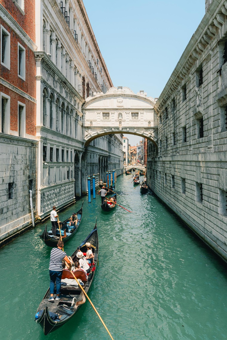 Zu den Venedig  Sehenswürdigkeiten gehört die Seufzerbrücke, die man im Bild sieht. Darunter fahren auf den türkisfarbenen Wasser des Kanals Gondoliere durch. 