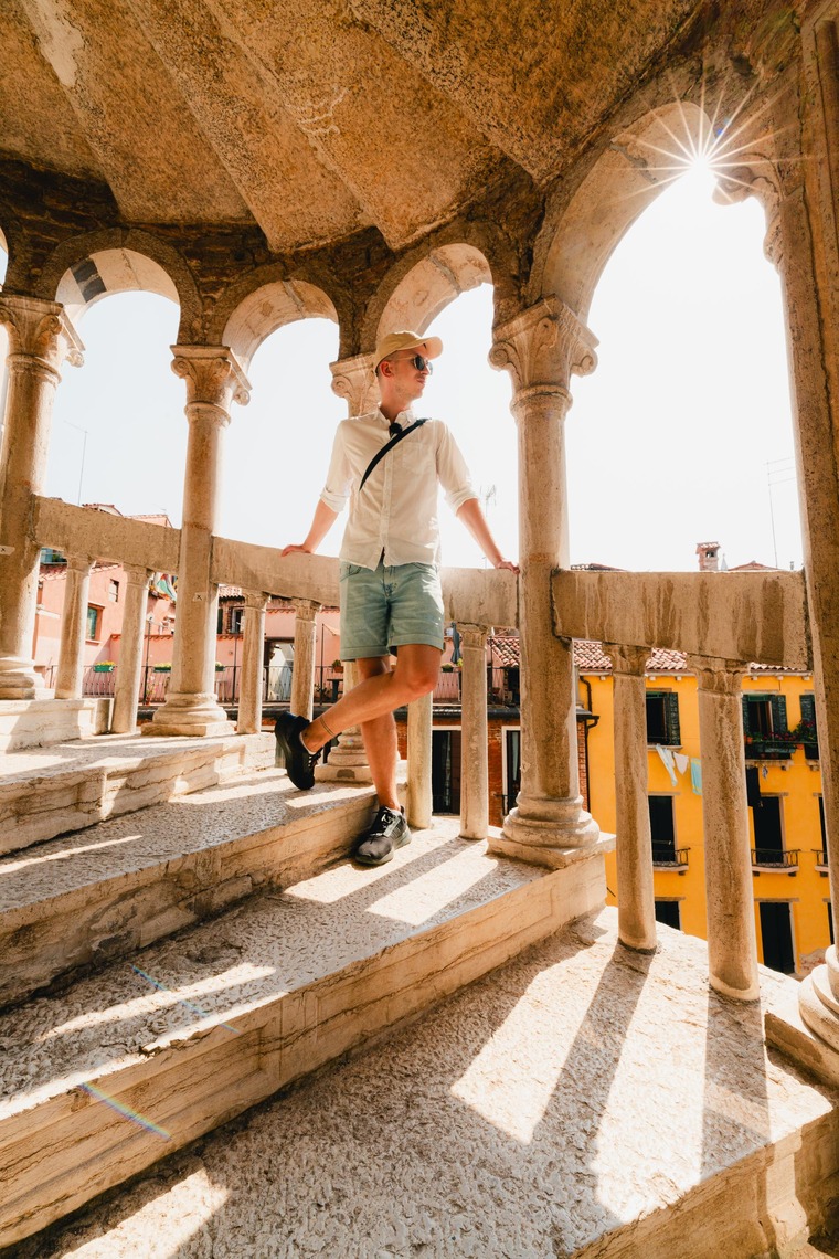 Zu den Venedig  Sehenswürdigkeiten gehört die Scala Contarini del Bovolo. Die Wendeltreppe ist ein Geheimtipp. Im Bild sieht man einen Touristen, wie er am Geländer der Treppe angelehnt steht. 