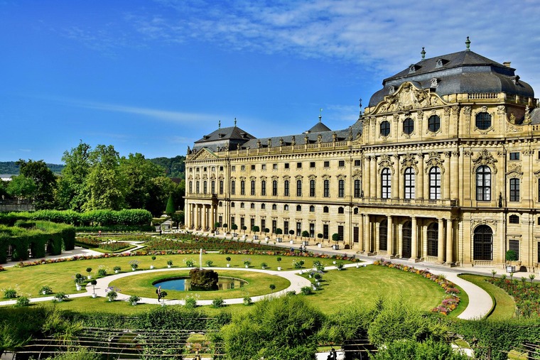 Zu den Sehenswürdigkeiten in Würzburg gehört die Residenz. Auf dem Bild sieht man das barocke Gebäude samt Garten.