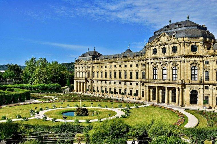 Zu den Sehenswürdigkeiten in Würzburg gehört die Residenz. Auf dem Bild sieht man das barocke Gebäude samt Garten.