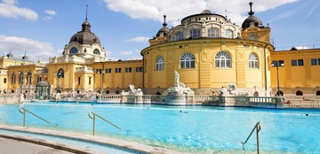 Budapest Thermen: Das Bild zeigt die  als Ausflugsziel ein schönes, gelbes Thermengebäude in Budapest. 