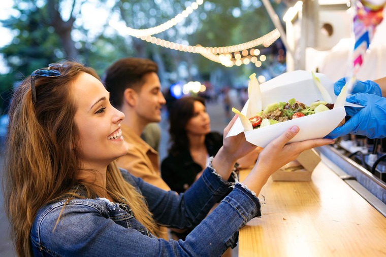 Events Österreich: Eine Frau nimmt ihre Essensbestellung an einem Food-Truck beim European Street Food Festival entgegen