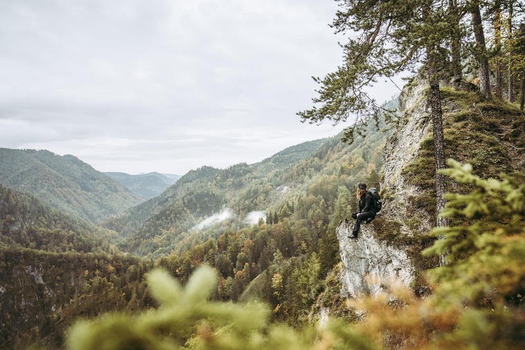 Wanderin sitzt und blickt in Richtung Hintergebirge