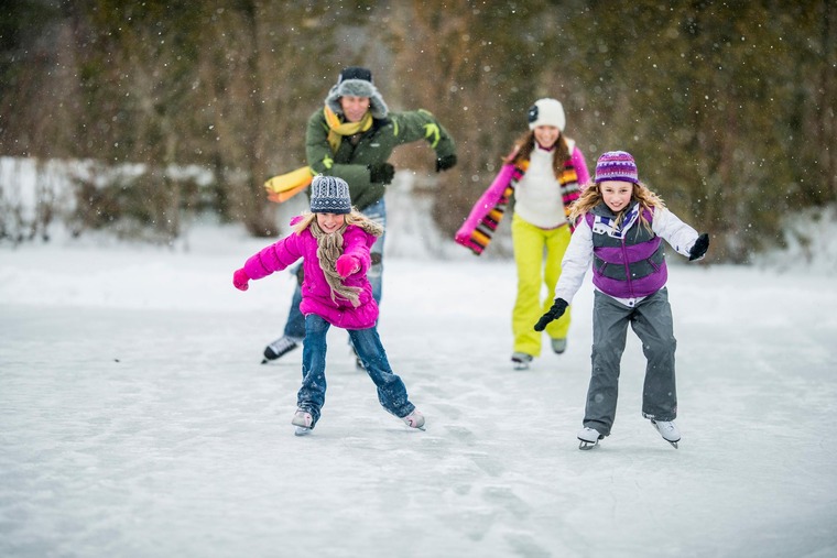 Erwachsene und Kinder fahren im Winter Schlittschuh