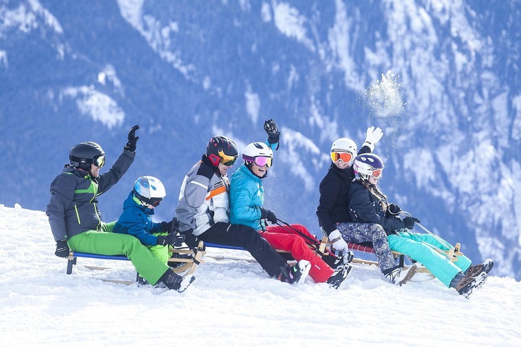 Familie auf einem Schlitten rodelt auf dem Berg