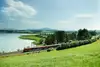 Railjet fahrend in der Landschaft. Im Hintergrund sieht man noch einen Fluss.