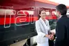 Frau und Mann in Businesskleidung stehen am Bahnsteig und schütteln Hände. Im Hintergrund steht ein Railjet.