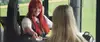 Frau mit roten Haaren im Bus sitzend und lächelnd, gibt Fahrgästin ein Fahrschein.