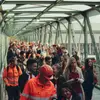 Eine Gruppe an ÖBB MItarbeiter:innen in unterschiedlichen Uniformen über eine Brücke gehend.