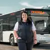 Frau in weißen Hand und schwarzen Gilet. Steht vor einem Postbus