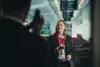 Eine weibliche Zugbegleiterin in einen Zug stehend, mit ÖBB Uniform lächelnd. 