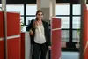 Junge Frau stehend angelehnt mit braunen langen Haaren und in die Kamera lächelnd