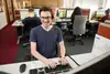 Mann mit Brille und T-Shirt am Computer sitzend.