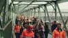 Eine Gruppe an ÖBB MItarbeiter:innen in unterschiedlichen Uniformen über eine Brücke gehend.