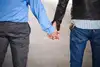 Ein Ausschnitt von hinten von zwei Männer händchenhaltend 