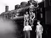Eisenbahner stehen vor und sitzen auf Lokomotive
