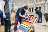 ÖBB Lehrling, der ein Graffiti-Bild mit Regenbogenfarben und der Aufschrift „QBB“ gestaltet. 