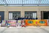 Die ÖBB Lehrlinge und die Graffiti-Workshopleiterin mit allen gestalteten Schildern und Bannern. Von links nach rechts: Ein lila Schild mit orangen Smileys und der Aufschrift Mensch = Mensch. Ein Schild mit der Progressive Pride Flagge und dem QBB Logo. Ein rosa Bild mit einer Kombination aus Unendlichkeitszeichen und den Zeichen für „weiblich“ und „männlich“ auf dem steht: „Mensch sein reicht“. Ein lila Bild mit fetten Lettern: „1 zig“ und dünnen Lettern: „artig“. Ein großes oranges Banner mit Tigeraugen, auf dem steht: „Tiger Stripes are not straight“.
