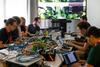 Teilnehmende arbeiten mit Laptops und technischer Hardware an einer Hackathon-Lösung.