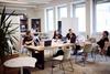 Eine Arbeitsgruppe bespricht ihre Ideen an einem Tisch mit mehreren Laptops.