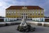 Ausflugstipp Niederösterreich: Das schöne Schloss Hof in NÖ. Auf dem Bild sieht man ein prachtvolles gelbes Gebäude mit einer Statue im Vordergrund.