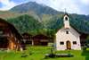 Zu Urlaub in Osttirol gehört ein Besuch von Innervillgraten. Auf dem Bild sieht man eine Kapelle und rustikale Häuser in den Bergen. 