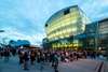 Zu den Sehenswürdigkeiten St. Pölten gehört das Landestheater. Auf dem Bild sieht man es bei Nacht, beleuchtet und mit vielen Passant:innen.