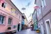 Blick in eine Altstadtgasse in Villach, mit bunten Häusern und Regenschirm-Dekoration. 
