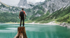 Wanderer auf einem Baumstumpf schaut auf klaren Bergsee