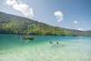 Urlaub am Weissensee: 2 Personen schwimmen im Weissensee, im Hintergrund ist auf dem See ein Ruderboot sichtbar.
