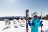 Skifahren in Österreich: Eine Skifahrerin steht, mit ihren Skiern in der linken Hand und den Skistöcken in der rechten Hand, auf der Piste vor dem Schriftzug STUHLECK, der in den Schnee gesteckt wurde. 