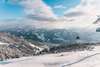 Skifahren in Österreich: Blick auf das Gletscherskigebiet Zell am See-Kaprun. Unter leicht bewölktem Himmel sieht man eine Piste, links im Bild eine Bergbahn. 