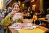 Zu den Bologna Sehenswürdigkeiten gehört auf jeden Fall die Kulinarik. Auf dem Bild sieht man eine Frau, die an einem Tisch im freien, vor einem Restaurant, Mortadella isst und dabei lächelt. 