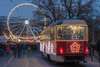 Zu den Brünn Sehenswürdigkeiten gehört der Weihnachtsmarkt. Auf dem Bild sieht man das Riesenrad und eine weihnachtlich geschmückte Straßenbahn vor dem Weihnachtsmarkt. 