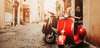 Geheimtipps Rom: Eine Gasse im sanften Licht, im Vordergrund sieht man eine rote Vespa. 