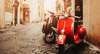 Geheimtipps Rom: Ein römische Gasse im sanften Licht, vorne sieht man eine rote Vespa. 