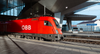 Günstig reisen: Man sieht eine rote ÖBB Lok am Bahnhof Wien Hauptbahnhof. 